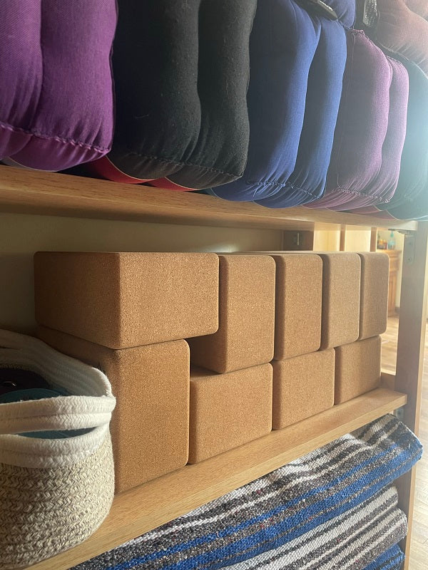 EcoBlock Cork Yoga Block by Asivana Yoga stacked on a yoga prop shelf.
