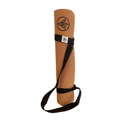 The Flux cork yoga mat standing with the 'Simple' yoga mat carrying strap ready to go